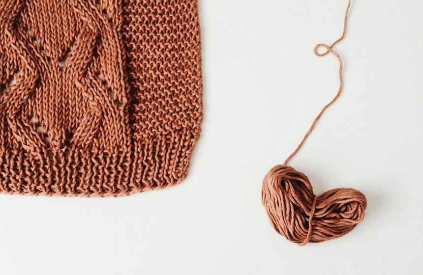 Próbka dzianiny — kwadratowa swatch z warkoczem i kłębek włóczki Kwadratowa próbka dzianiny w stylu stockinette z warkoczem obok kłębka włóczki — próbka obliczeniowa na drutach
